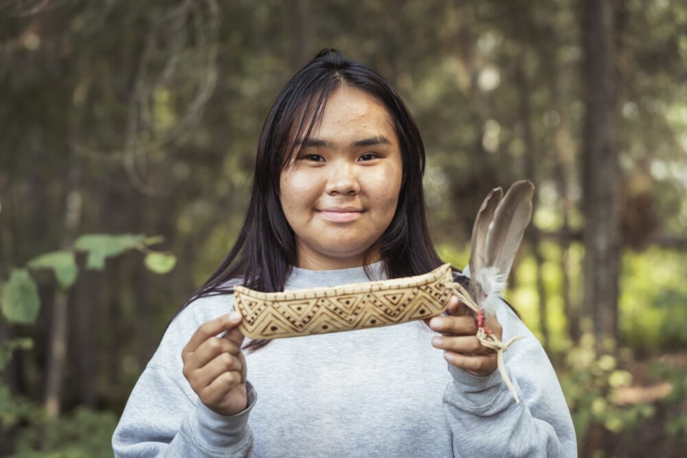 Jeune Autochtone tenant dans ses mains un petit canot d'écorce.