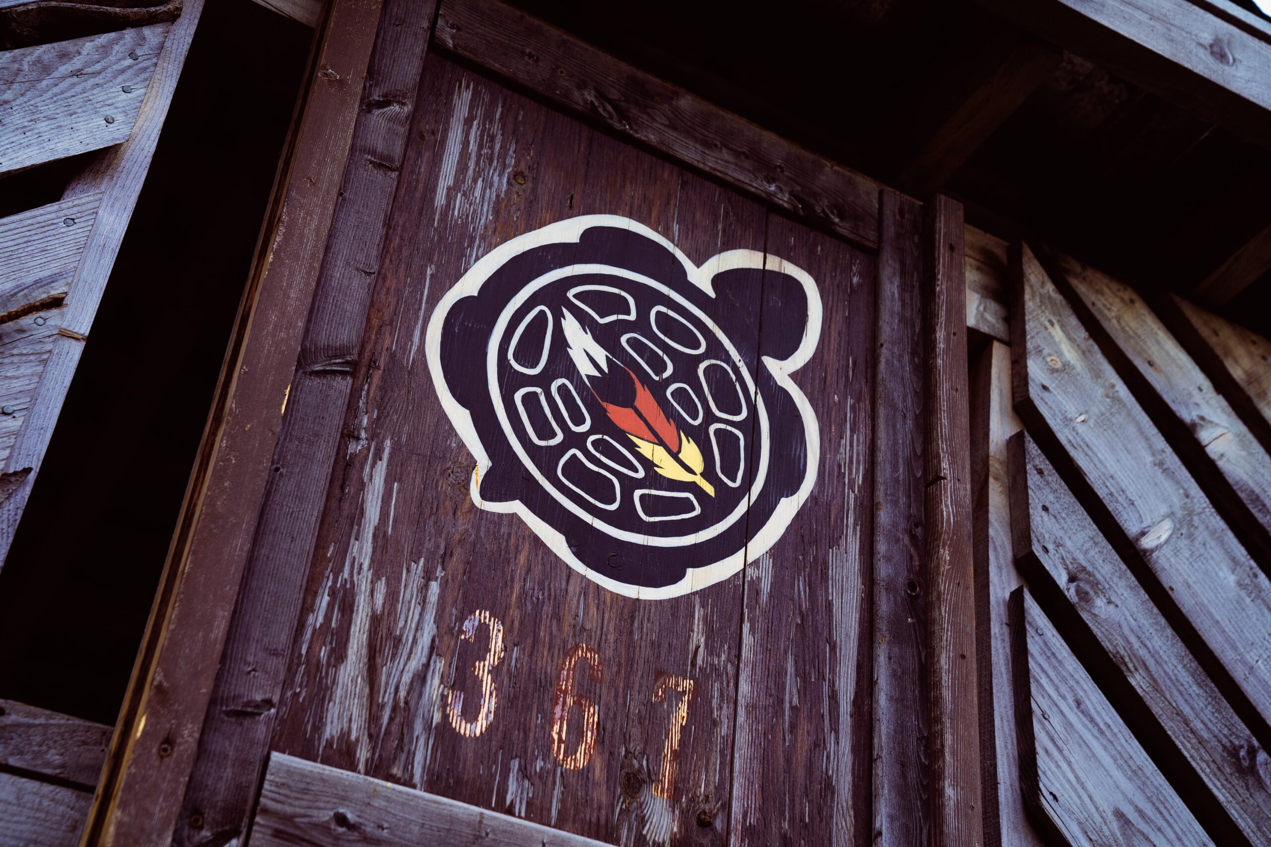Symbole autochtone représentant une tortue avec une plume et les couleurs de la roue de médecine, peint sur une structure en bois.