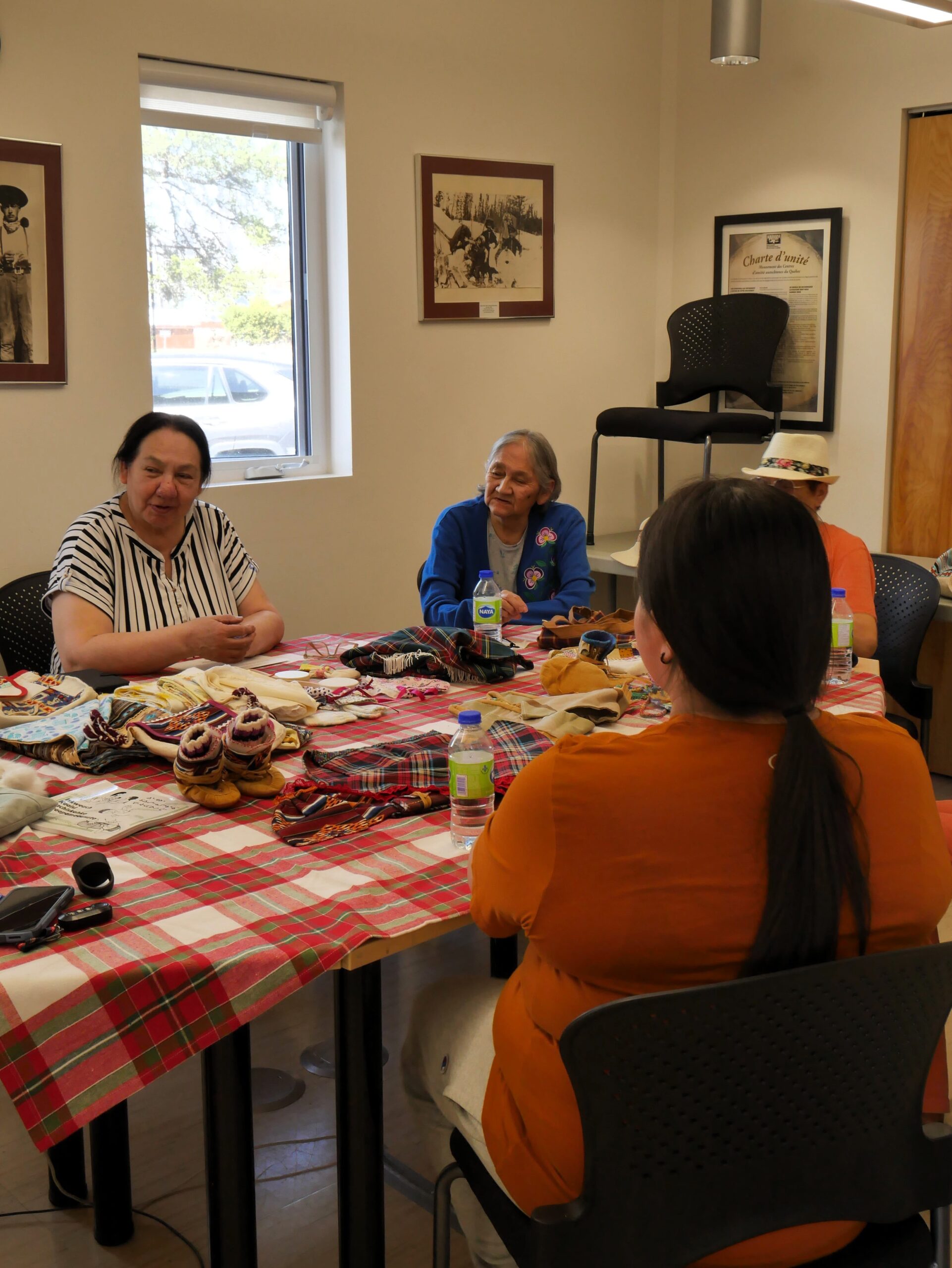 Aînés et employés réunis autour d’une table dans un Centre d’amitié autochtone, participant à une activité artisanale.