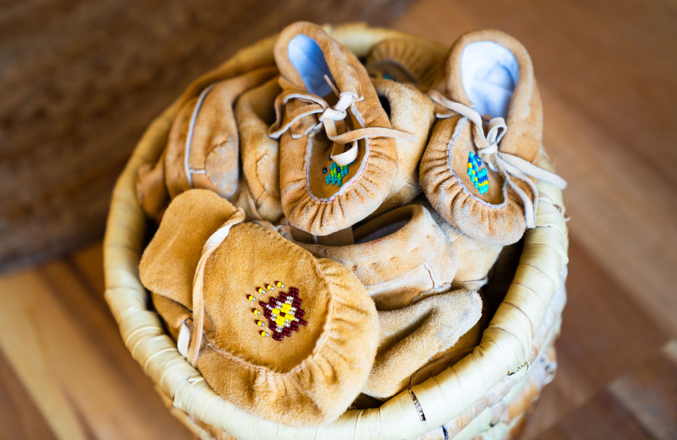 Panier contenant des mocassins autochtones ornés de perles colorées, symbole du savoir-faire traditionnel au sein des Centres d’amitié.