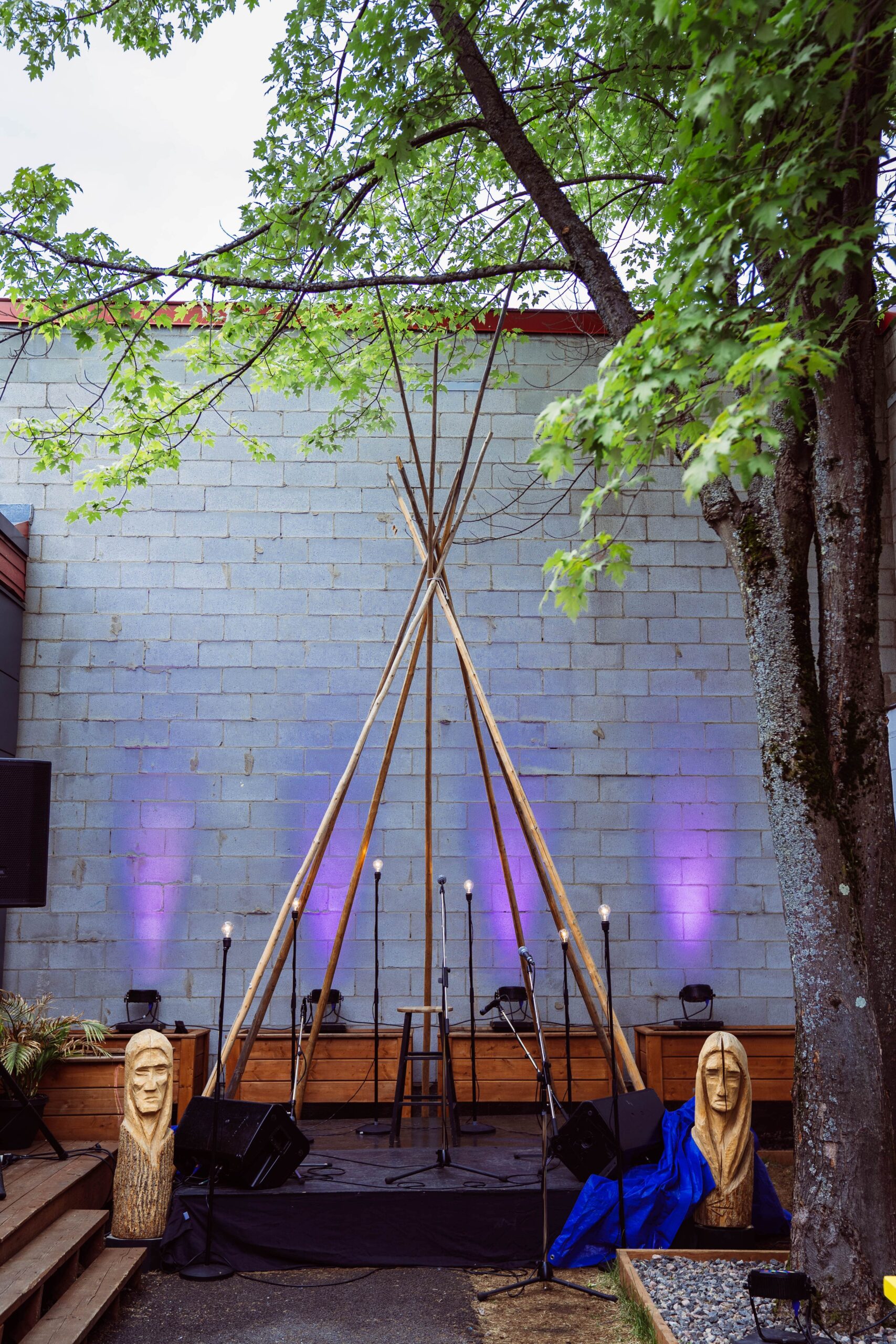 Structure extérieure en forme de tipi avec statues en bois et éclairage violet près du Centre d’amitié autochtone Capetciwotakanik - La Tuque.