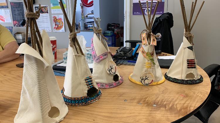 Mini tipis décorés avec motifs traditionnels autochtones sur une table en bois, utilisés pour un atelier culturel.