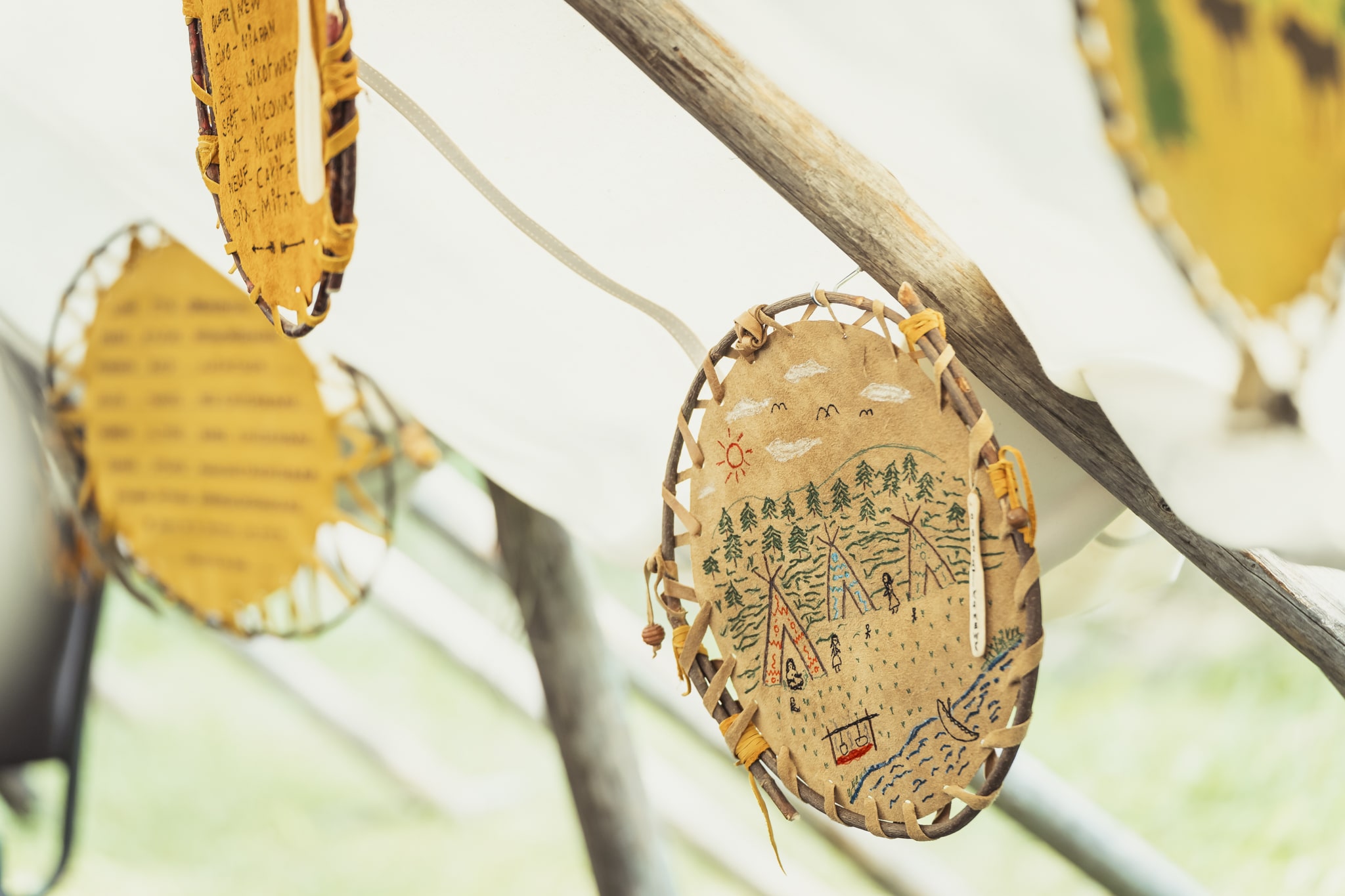 Pièce d’artisanat autochtone en écorce décorée de motifs traditionnels suspendue sous une structure en bois