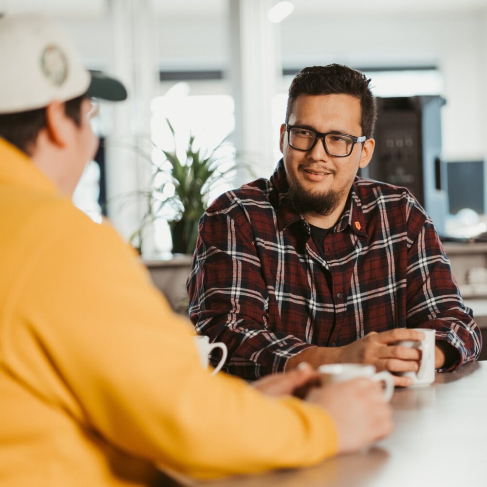 Employés d’un Centre d’amitié discutant autour d’une table avec des tasses de café.