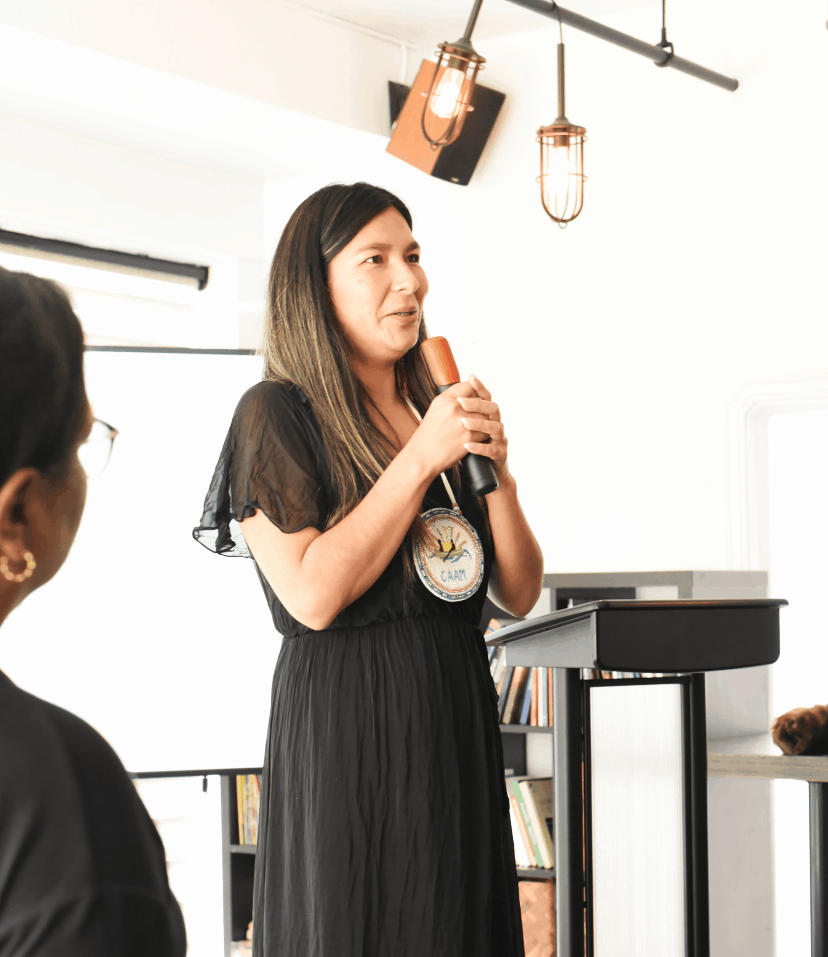 Personne prenant la parole avec un micro à l'intérieur d'un Centre d'amitié.