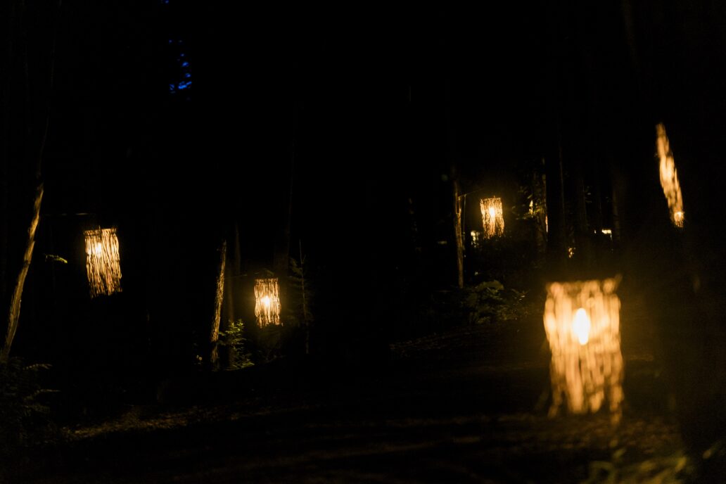 Lampes artisanales éclairant un sentier forestier la nuit, créant une ambiance chaleureuse