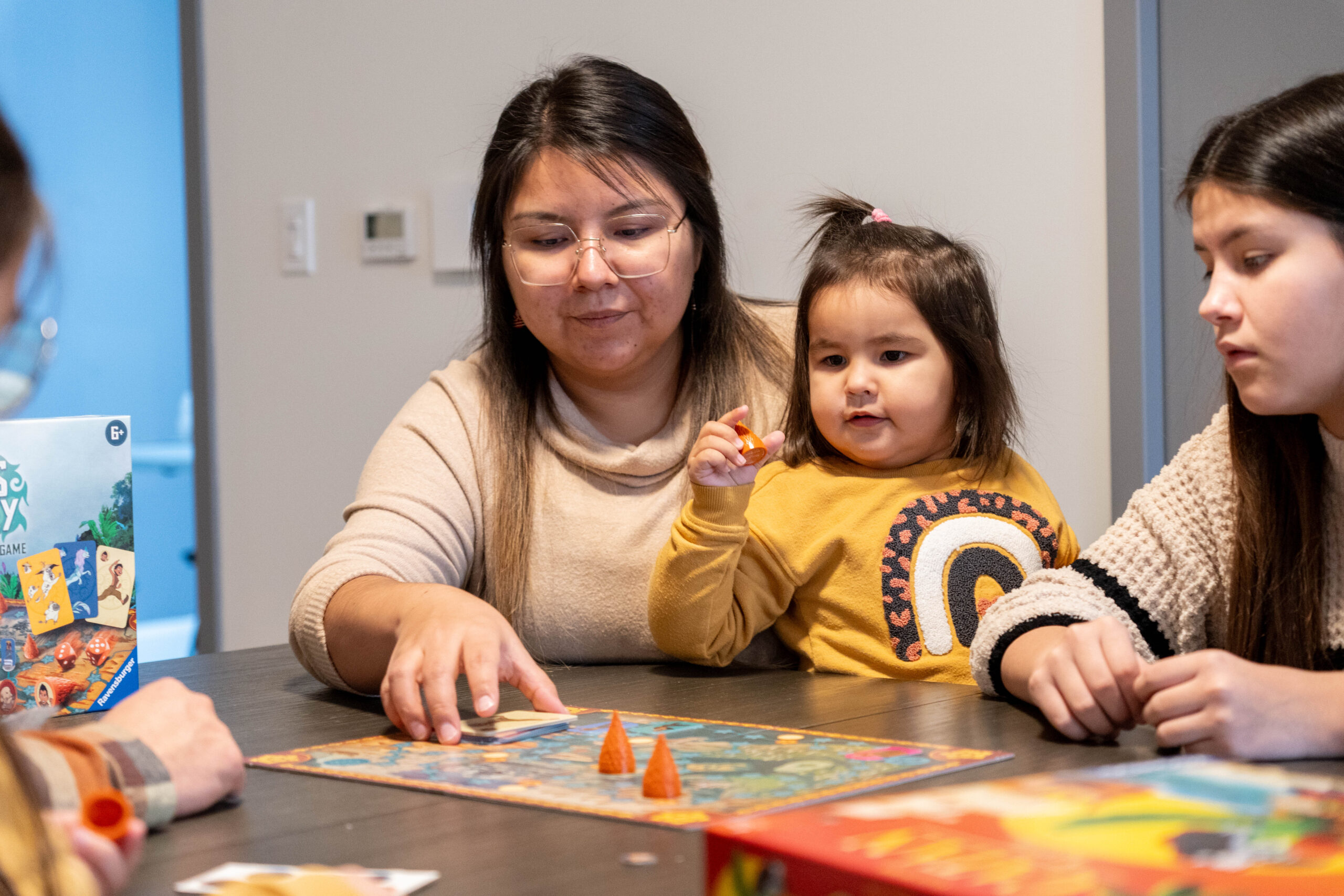 Famille autochtone jouant à un jeu de société autour d’une table dans un milieu de vie de la SIRCAAQ.
